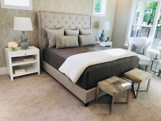 bedroom overview of bed, side table, lamp and patterned textured wallpaper