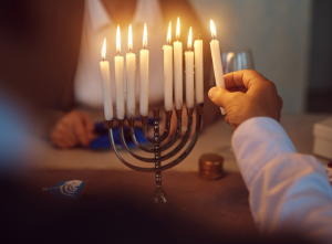 person lighting hanukkah candles